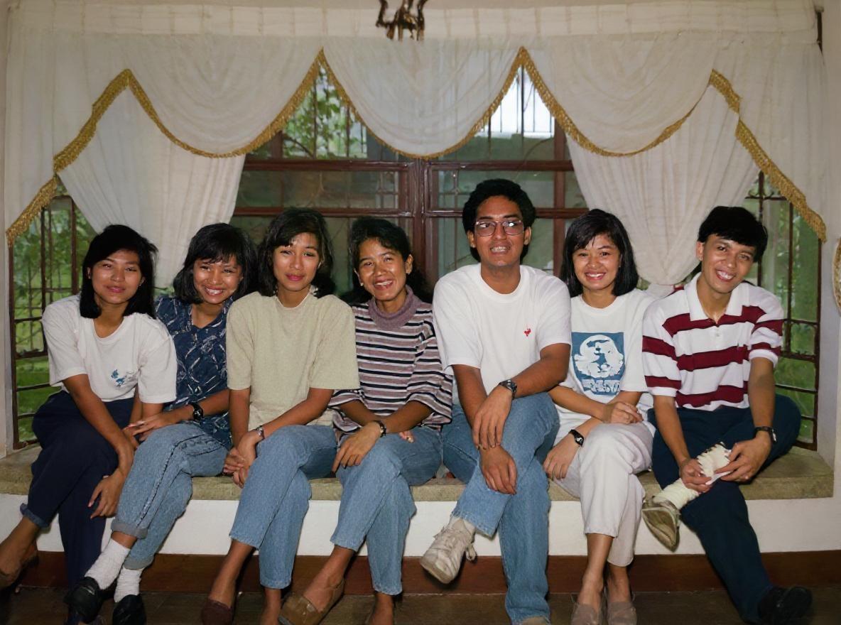 Restore and colorize old  photograph of these group of filipino brown skin not caucasian skin tone with high fidelity. Enhance the image to achieve sharp, high-resolution quality while preserving the original facial features,  hair details, setting, and outfits. Accurately reconstruct any scratches, tears, overexposed  light or faded areas, ensuring seamless blending with the original content. Apply natural, historically plausible colors to skin tones, clothing, and background elements, maintaining the authenticity of the scene. The output should be a vibrant, clear, and realistic colorized image that retains the exact composition and details of the original photograph, with no alterations to the subject's appearance or setting.